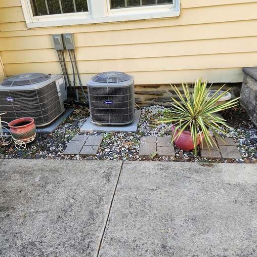 Before: two air-conditioning condensers beside a house on loose gravel and scattered pavers, next to a cracked concrete walk.